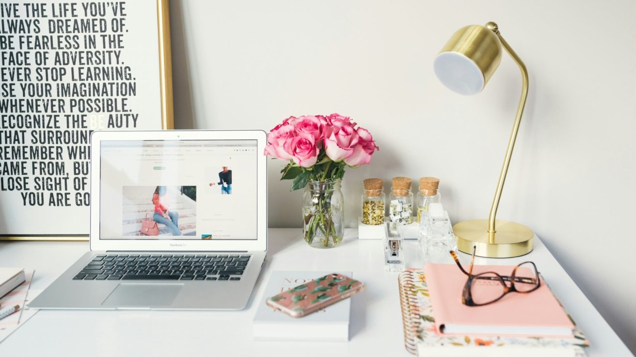 MacBook Air beside gold-colored study lamp and spiral books