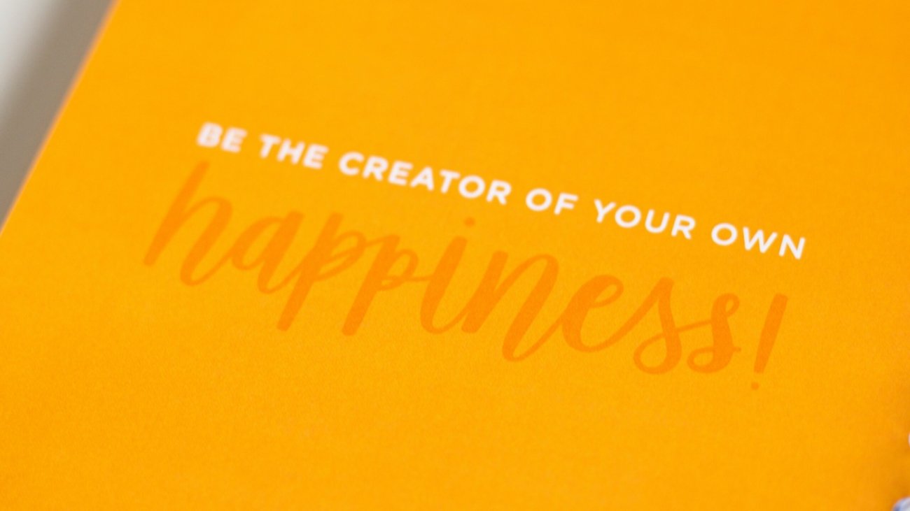 a yellow greeting card with the words be the creator of your own happiness